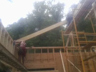 Carpenter raising a rafter beam on a new second story frame in Orem