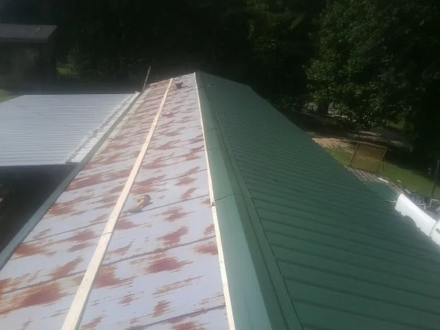 Old rusted panels beside newly installed green metal roofing — Wind Damage Roof Repair by Roofing Brothers in Orem
