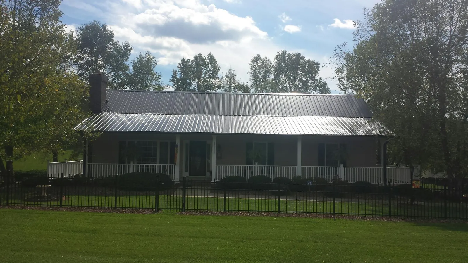 Gray metal roof on a brick ranch with a full width front porch — Gutter Guard Installation work by our crew in Orem