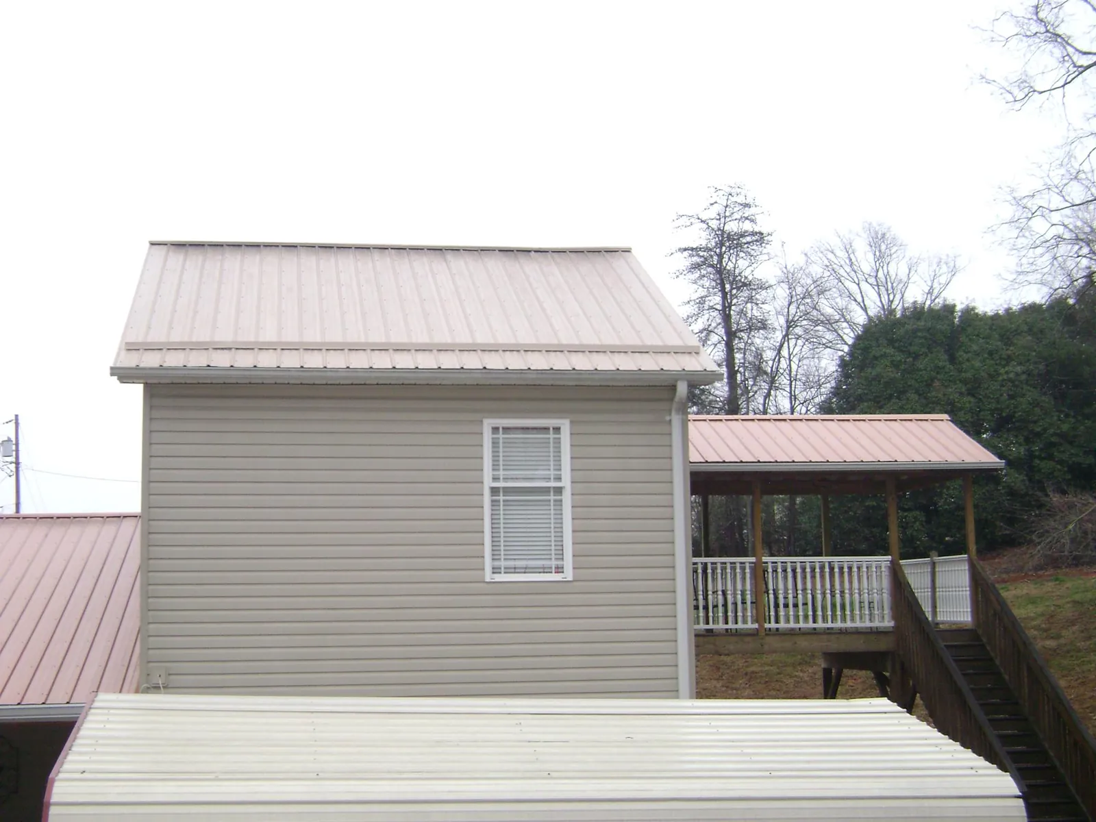 Tan metal roofs on a two story addition and attached porch, from a Roof Replacement job in Orem